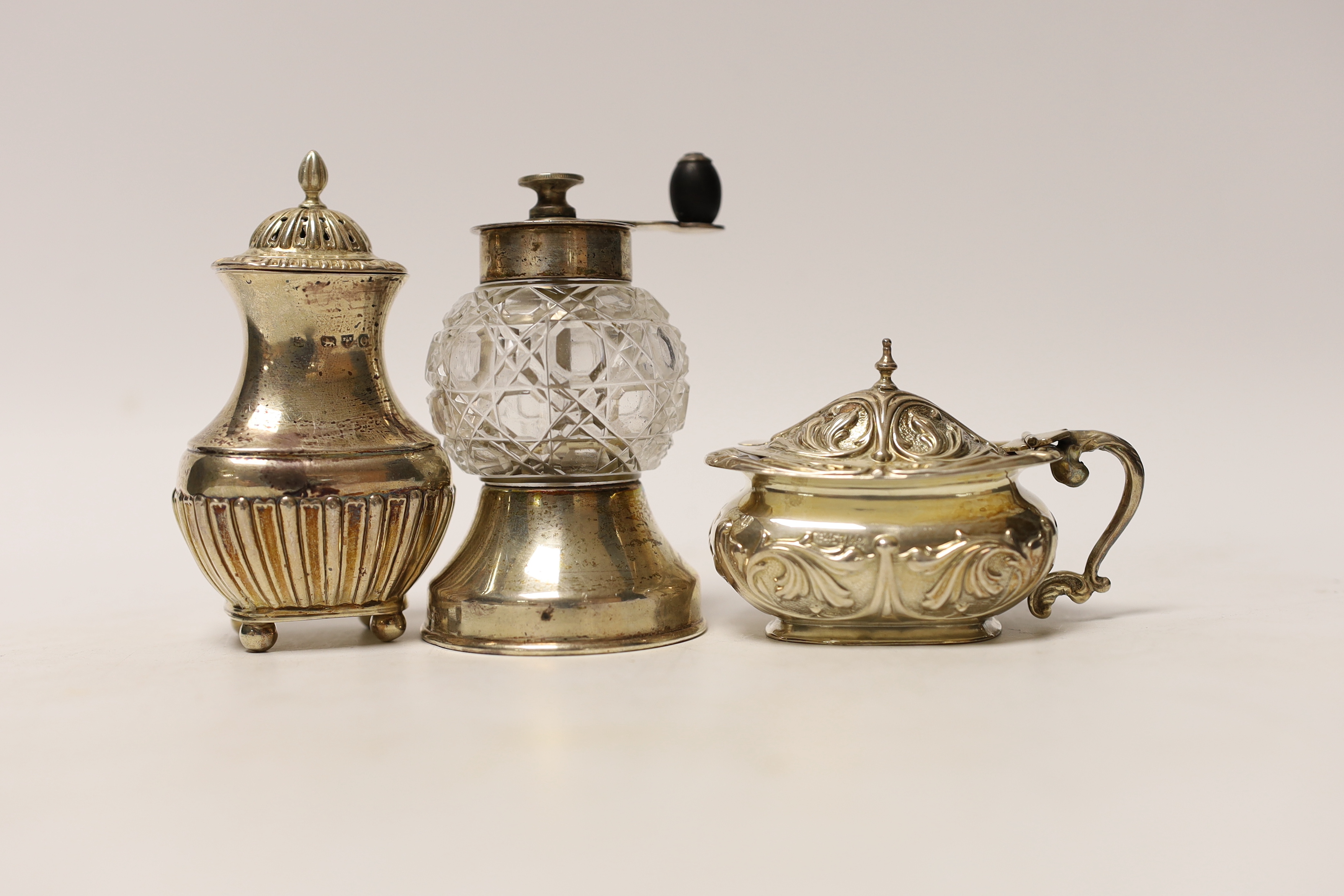 Seven assorted silver condiments, including a pepper grinder and salt and pepper mills.